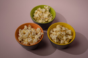 Popcorn looked down from above on a yellow background. The bowl of popcorn was lying flat. Top View.