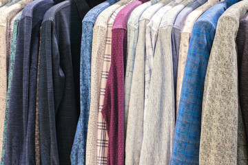 Obraz premium Fashion clothes on clothing rack - bright colorful closet. Closeup of rainbow color choice of trendy female wear on hangers in store closet or spring cleaning concept. Summer home wardrobe.
