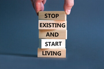 Stop existing start living symbol. Concept words Stop existing and start living on wooden blocks. Beautiful grey table grey background. Business Stop existing start living concept. Copy space.