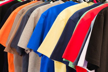 Fashion clothes on clothing rack - bright colorful closet. Closeup of rainbow color choice of trendy female wear on hangers in store closet or spring cleaning concept. Summer home wardrobe. t-shirts