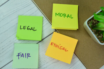 Concept of Legal, Moral, Fair, Ethical write on sticky notes isolated on Wooden Table.