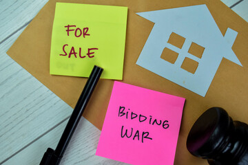 Concept of For Sale and Bidding War write on sticky notes isolated on Wooden Table.