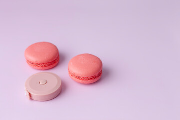 Pink macaroon and round tape measure on pink background top view