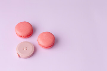 Pink macaroon and round tape measure on pink background top view