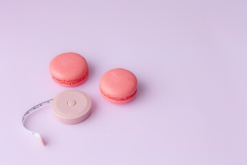 Pink macaroon and open round tape measure on pink background top view