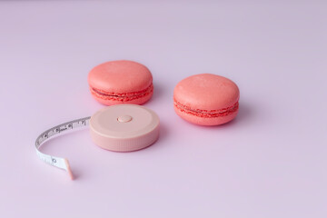Pink macaroon and open round tape measure on pink background top view
