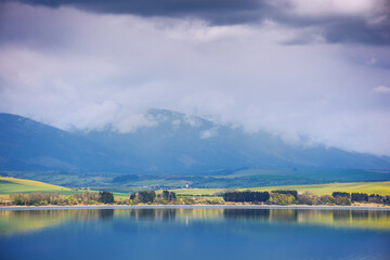 lake near the liptovsky mikulas, slovakia. liptovska mara water reserve in front of tatra mountains in spring. beautiful landscape on a cloudy afternoon