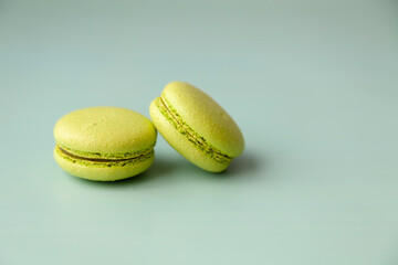 Two green macaroons on green background close up copy space