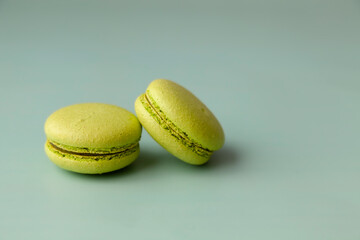 Two green macaroons on green background close up copy space