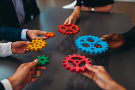 Businessteam work together and combine pieces of gears. Partnership and integration concept
