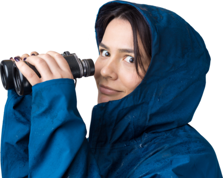 A tourist girl in a blue raincoat holds binoculars in her hands and looks into the distance, spies. - Powered by Adobe