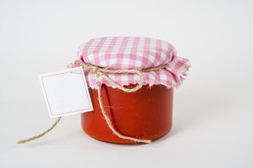 Canned homemade tomato paste jar with empty label isolated on white background.