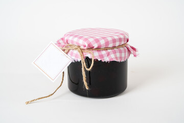 Small glass jar of homemade jam or marmalade with empty label isolated on white background.