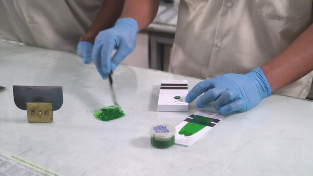 Workers with gloves doing sample test of green paint