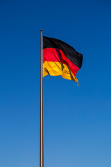 German flag on a flagpole against the blue sky