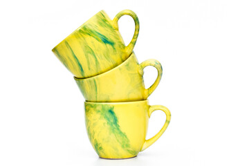Three cups stacked. Colored mugs. Colorful image with tableware. Isolated yellow utensil. Family dishes with different colors.