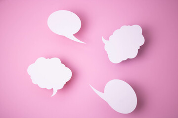 Paper templates in the form of clouds and bubbles for messages on a pink background.