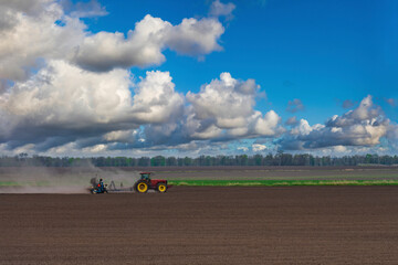 Red tractor plows the farm field.