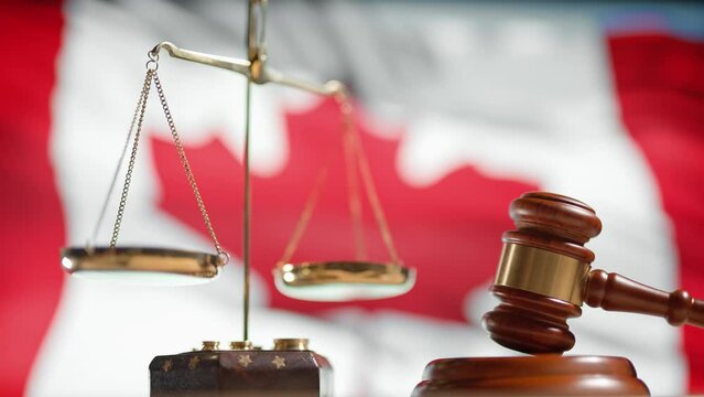 A judge gavel with a flag of Canada on background. Close up of wooden hammer and legal lawyer books or codex. Sentence law or legal system and jurisprudence or court concept.