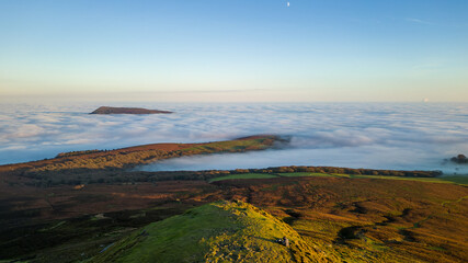 Aerial view of hillsides above a temperature inversion and sea of fog at sunset
