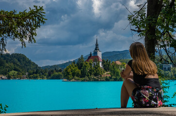 Young blonde girl from behind enjoying the turquoise waters of Lake Bled (Slovenia)