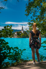 Obraz premium Young blonde girl from behind enjoying the turquoise waters of Lake Bled (Slovenia)