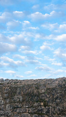 Nubes blancas y cielo azul sobre muro de piedra