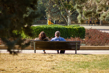 adult couple sitting on a bench in the park resting