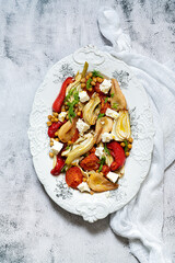 Roasted vegetables with herbs and spices on a white plate. Healthy mediterranean food. Top view.