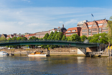 Obraz premium Cityscape of Bremen with old architecture, historical wooden sailing ships and barge floating along the river Weser. Bremen, Germany, July 15, 2021