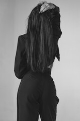 Unrecognizable young woman in a black jacket on her shoulder, rear view
