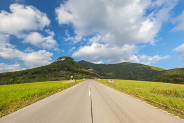 Summer landscape with a road going up to hills.