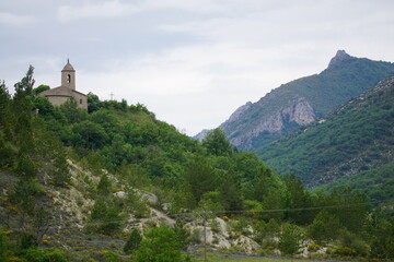 Fototapeta na wymiar landscape with old stone church on top of the hill of St Vincent sur Jabron and mountains in the south of France