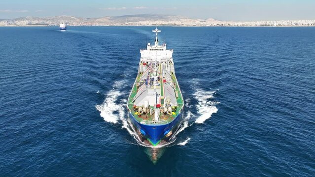 Aerial drone loop video of industrial liquified LPG gas tanker cruising near gas terminal