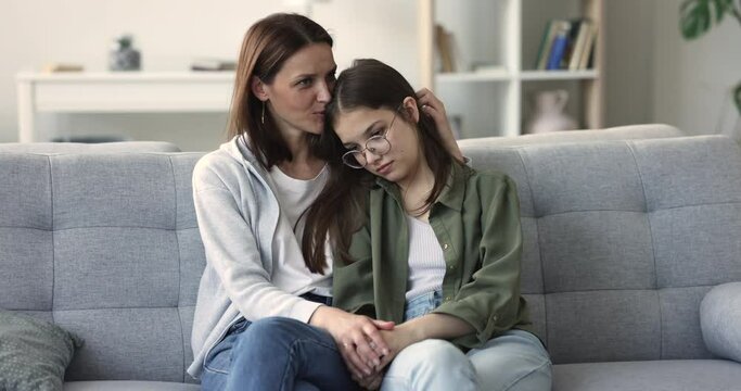 Sad teenager girl talks to caring caressing mother. Loving mature mum, soothes her adolescent daughter, express support, touch, strokes hair, give advice to concerned child. Motherhood, teen problems