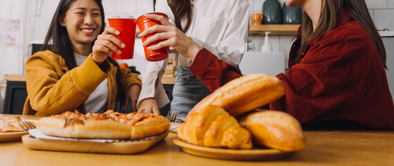 Young woman eating pizza and laughing while sitting with her friends in a restaurant. Group of friends enjoying while having food and drinks at cafe.