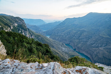 Fototapeta na wymiar Beautiful panoramic view of the mountains with bushes, rocks and a blue-green river on a summer day at sunset. Sulak Canyon. Dagestan