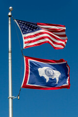 Wyoming state flag and the American flag waving in a blue sky