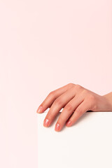 female hand with japanese manicure on a pedestal on a pink background
