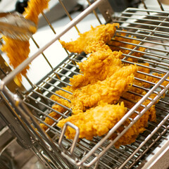 Cooking breaded chicken slices in the kitchen in fast food restaurant