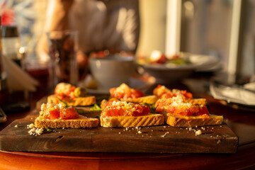 Fototapeta na wymiar Tasty crunchy Italian snack bruschetta with chopped tomatoes and parmesan cheese on wooden board.