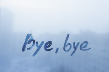 Fototapeta na wymiar lettering Bye, bye on foggy glass on blue window