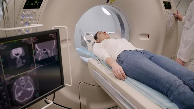 4k video CT scan of brains of woman in medical clinic. Girl patient is doing computed tomography x-ray examination of tumor in his head in a CT scan room.
