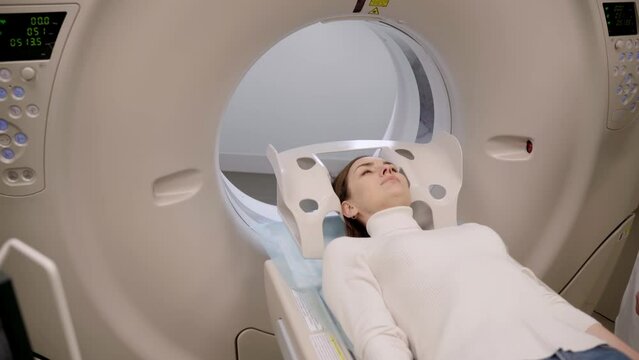 4k video CT x-ray examination of lung cancer in medical clinic. Patient girl lies on computed tomography bed and scanning lungs for diagnose lung cancer in medical clinic.