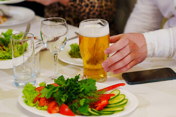 a glass of cold foamy beer on the snack table. 