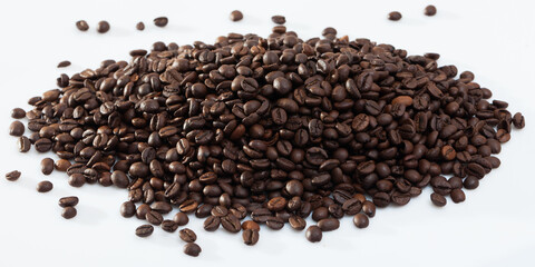 Pile of aromatic roasted coffee beans on white surface..