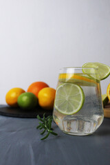 lemonade citrus orange lime lemon in a glass with ice and rosemary on a gray background next to the fruits close-up. Preparation of lemonade drinks summer refreshing drinks. health care