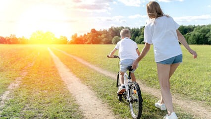 Obraz premium mom teaches her son to ride a bike
