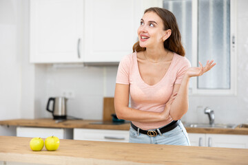 Portrait of positive girl housewife standing at home kitchen