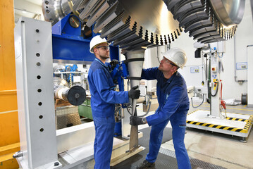 workers assembling and constructing gas turbines in a modern industrial factory